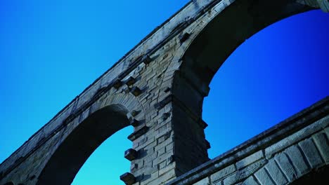 Large-stone-arches-of-a-Roman-water-pipe-under-a-blue-sky-in-France-Pont-du-Gard