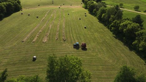 Tractor-With-Baler-Working-Over-Green-Hay-Field-In-Oronoco,-Minnesota,-USA---aerial-shot