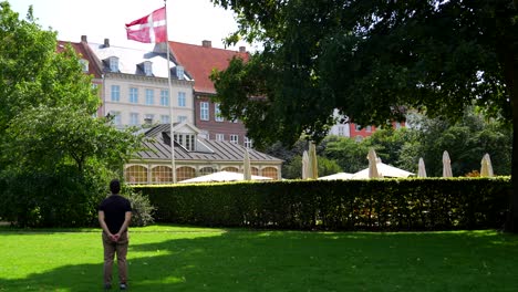 Man-proudly-looking-at-a-Danish-flag-waving-in-a-windy-day-in-park