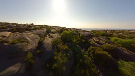 FPV-drone-flying-low-over-treetops-and-cliffs-in-Ramsvik,-Sweden