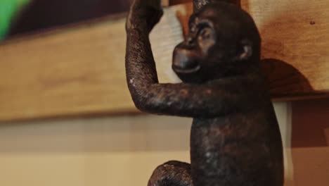 Schwarze-Statue-Eines-Affen,-Zoom-In-Filmmaterial-Mit-Holzhintergrund