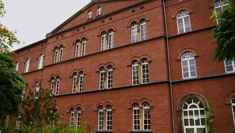 Altes-Backsteinhaus-Mit-Großen-Weißen-Fenstern-Mit-Grünem-Bauch-Im-Fenster