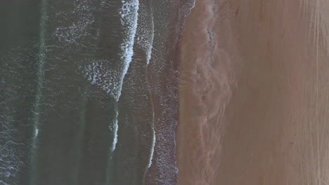 Aerial:-Top-down-orbit-shot-of-a-sand-beach-near-Katakolo-with-seaside-houses-during-dusk