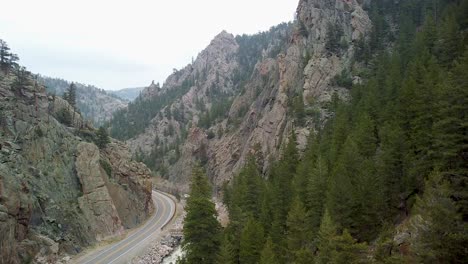 Aerial-ascent-of-road-along-river-through-steep-rock-cliffs,-Colorado