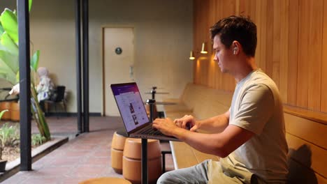 Digital-Nomad-Working-on-Modern-Laptop-Computer-Inside-Coffee-Shop---Profile-View