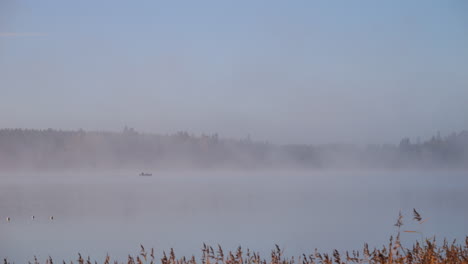 Morning-fog-hazy-peaceful-lake-with-small-fishing-boat,-Autumn-stillness