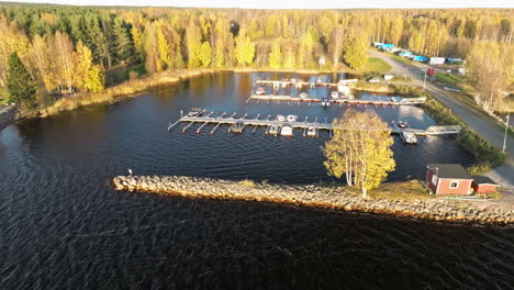 Sweden---Boats-in-a-Lakeside-Harbor-with-a-Forest-Backdrop-on-a-Breezy-October-Day,-as-the-Setting-Sun-Bathes-the-Scene-in-Warm,-Vibrant-Autumn-Colors---Aerial-Drone