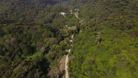 Imágenes-De-Drones-Aéreos-De-4k-En-Cámara-Lenta-Descendiendo-Sobre-Un-Camino-De-Tierra-En-Los-Bosques-Tropicales-De-Costa-Rica,-Monteverde