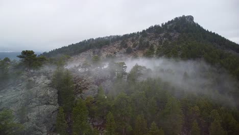 Aerial-still-view-of-fog-creeping-over-rock-ridge-at-Eagle-Cliff-Mountain,-Estes-Park,-Colorado