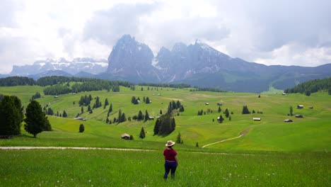 Rear-shot-of-a-woman-putting-on-a-hat-and-contemplating-the-Seiser-Alm,-Italy