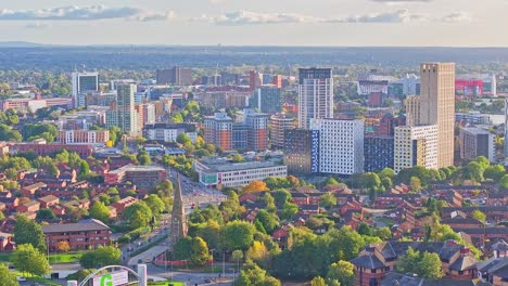 Aerial-view-of-City-of-Manchester-with-tower-buildings-and-church-with-traffic-in-road-during-sunny-day---Landing-flight