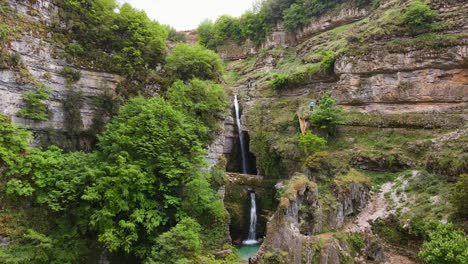 Luftaufnahme-Des-Malerischen-Peshtura-Wasserfalls-Und-Der-Canyonlandschaft-In-Albanien,-Mit-Einigen-Kletternden-Personen