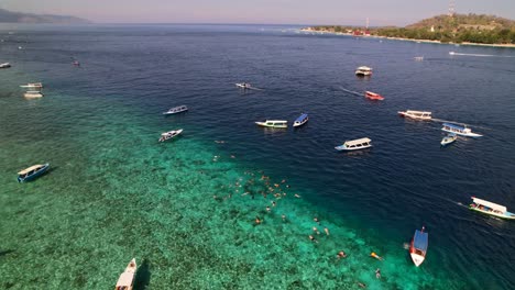 Tour-Travel-Boats-Anchored-in-Turquoise-Water-for-Tourists-Snorkeling-and-Swimming-in-Gili-Indonesia---Aerial-view