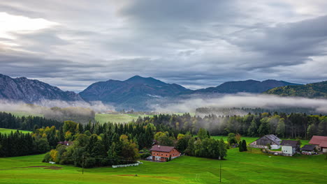 Rural-Village-With-Farmhouses-Surrounded-By-Mountain-Ridges-During-Foggy-Day-In-Austria