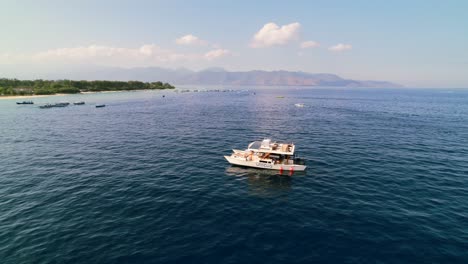 Barco-Catamarán-De-Lujo-Con-Turistas-A-Bordo-Navegando-Por-La-Costa-De-Las-Islas-Gili-En-Indonesia---Paralaje-Aéreo