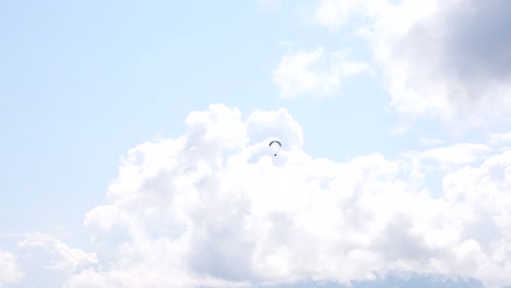 Paratrooper-in-the-sky-on-a-colorful-parachute-flying-between-clouds,-sunny-day