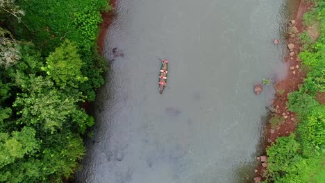 An-aerial-view-captured-by-a-drone-showcases-a-serene-scene-of-a-small-rowboat-peacefully-traversing-a-beautiful-river-in-the-heart-of-the-jungle