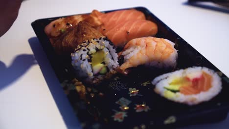 Closeup-macro:-Chopsticks-grab-salmon-nigiri-sushi-from-ornate-plate