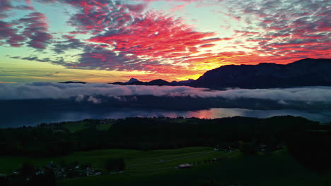 Drone-shot-panning-over-the-countryside-with-a-mountainous-sunset-sky-background-in-Austria