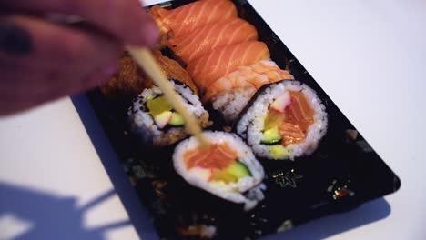 Chopsticks-attempt-to-pick-up-dragon-sushi-roll-on-narrow-focus-plate