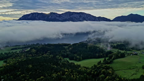 Magical-Austria-landscape-with-clouds-and-mountain-peeks-above,-aerial-view