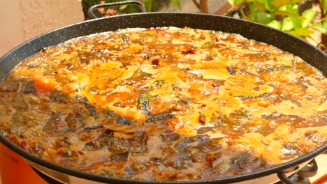 Close-up-shot-of-traditional-paella-with-rice-and-chicken,-been-cooking-in-traditional-pan-in-Valencia,-Spain-at-daytime