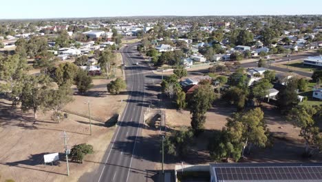 Drone-flying-over-a-motel-with-solar-panels-on-roof-and-a-road-in-a-small-town-of-Australia