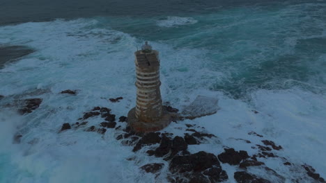 Mangiabarche-Lighthouse,-Sardinia:-orbital-aerial-view-of-the-beautiful-lighthouse-and-with-the-crashing-waves