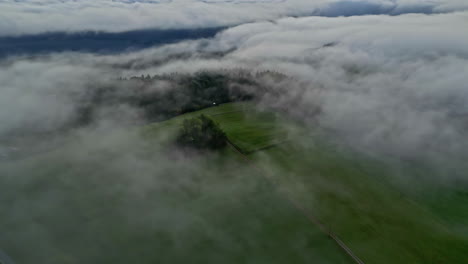 Aerial-shot-a-of-green-landscape-with-cloud-and-mist-hovering-over-it
