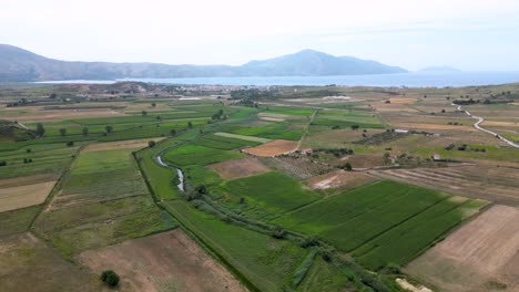 Farmland-and-farming-fields-situated-near-the-sea-with-mountains-in-the-background