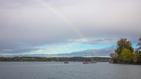 Rainbow-over-lake-Attersee-and-sailboats,-time-lapse-view