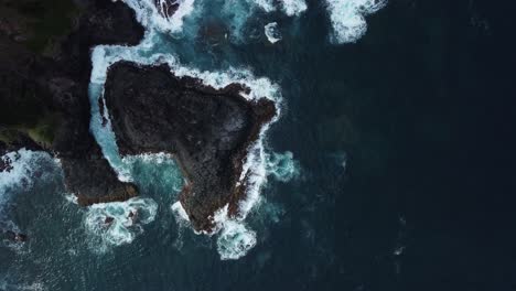 Aerial-birdseye-shot-off-the-majestic-coast-of-norfolk-island,-australia-with-views-of-the-rocky-terrain,-deep-blue-sea-with-foaming-waves-and-natural-beauty-of-the-island-on-a-exciting-expedition