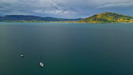 Drone-shot-of-the-Lake-Attersee-with-boats-and-mountain-peaks-with-thick-vegetation