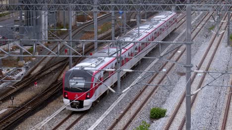 Red-and-white-colored-train-slowly-running-and-crossing-on-a-railway-switch-moving-forward-away-from-the-station