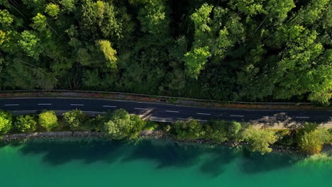 Aerial-clip-capturing-a-thin-road-with-forest-on-left-side-and-river-bank-on-the-right-side