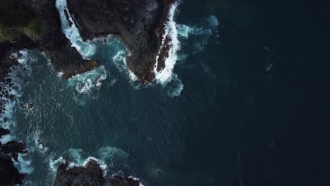 Aerial-birdseye-view-off-the-majestic-coast-of-norfolk-island-with-views-of-the-rocky-terrain,-deep-blue-sea-with-foaming-waves-and-natural-beauty-of-the-island-on-a-exciting-journey-through-australia