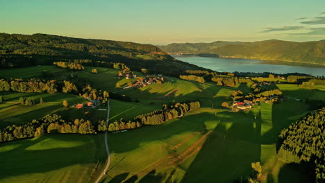 Meadows,-villages-and-lake-Attersee-in-distance,-aerial-view