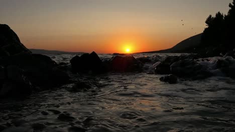 Waves-crashing-at-sunset-at-shoreline,-magical-mood-at-golden-hour-by-the-sea