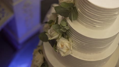 Elegante-Weiße-Hochzeitstorte,-Geschmückt-Mit-Frischen-Rosen-Und-Blattwerk