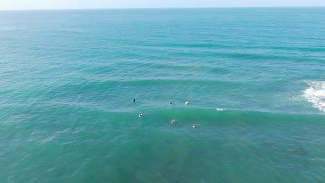 Drohnenansicht-Des-Strandes-Von-Costa-Rica-Zeigt-Surfer-Auf-Ihren-Tischen,-Die-Auf-Eine-Welle-Warten