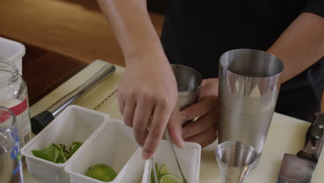 Bartender-adding-fresh-lime-and-sugar-in-mixer-then-using-a-muddler