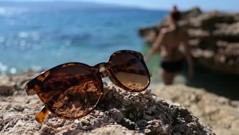 Sunglasses-with-sea-view,-woman-go-swimming,-relaxing-vacation-mood-by-the-sea