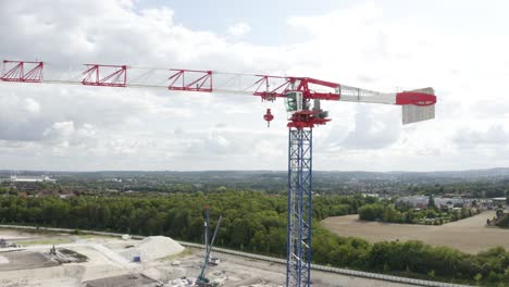 Aerial-drone-tilt-up-shot-of-a-large-crane-inside-new-constructions-development-site-on-a-cloudy-day