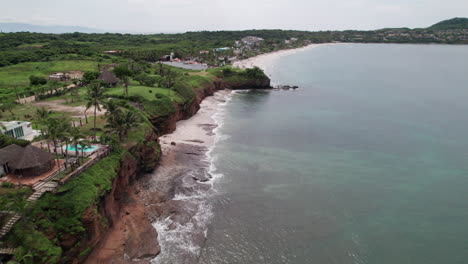 Drone-flies-parallel-to-the-unspoiled-green-coast-of-Careyeros-Beach,-land-on-the-left-and-sea-on-the-right