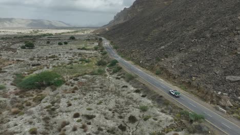 Drohne-Folgt-Einem-Auto-Auf-Der-Straße-Zwischen-Dem-Felsigen-Berg-Und-Dem-Tal-In-Hingol-Belutschistan,-Pakistan