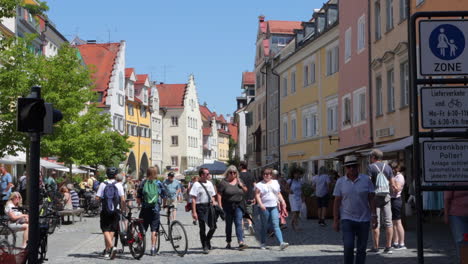Pedestrians,-cyclists-exploring-cobblestone-street,-shops-in-Lindau,-Germany