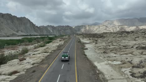 Drohne-Verfolgt-Einen-Jeep-Wagen-Auf-Der-Straße,-Der-In-Richtung-Einer-Wunderschönen-Berg--Und-Hügellandschaft-Hingol-Belutschistans-Fährt