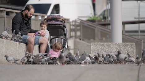 Father-and-his-two-kids-feeding-pigeons-in-slow-motion-scene
