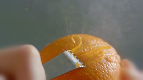 Nahaufnahme-Einer-Orangenschale,-Die-Mit-Einem-Zestenschneider-Gerieben-Wird