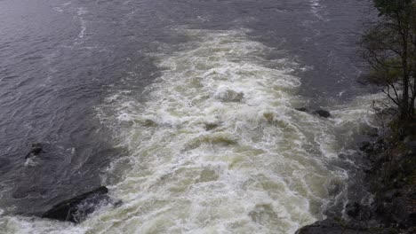 River-floodwater-rushing-out-to-fjord-during-heavy-rain,-Norway